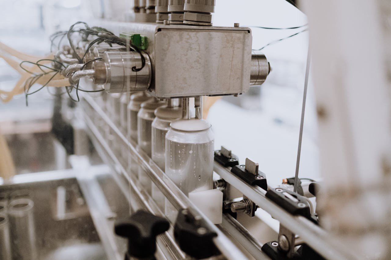 Home Close-up of an automated can filling machine in a beverage production line.